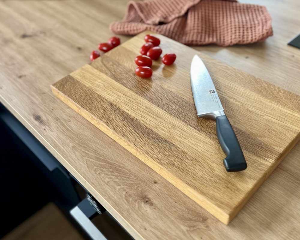 Längsholz-Schneidebrett auf dem Tomaten und Messer liegt